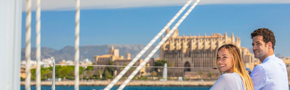 Ein Paar an Bord einer Segelyacht vor der Kathedrale La Seu in Palma