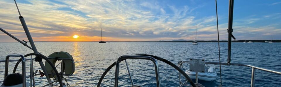 Sonnenuntergang über dem Wasser mit Blick vom Cockpit von einer Segelyacht auf Mallorca